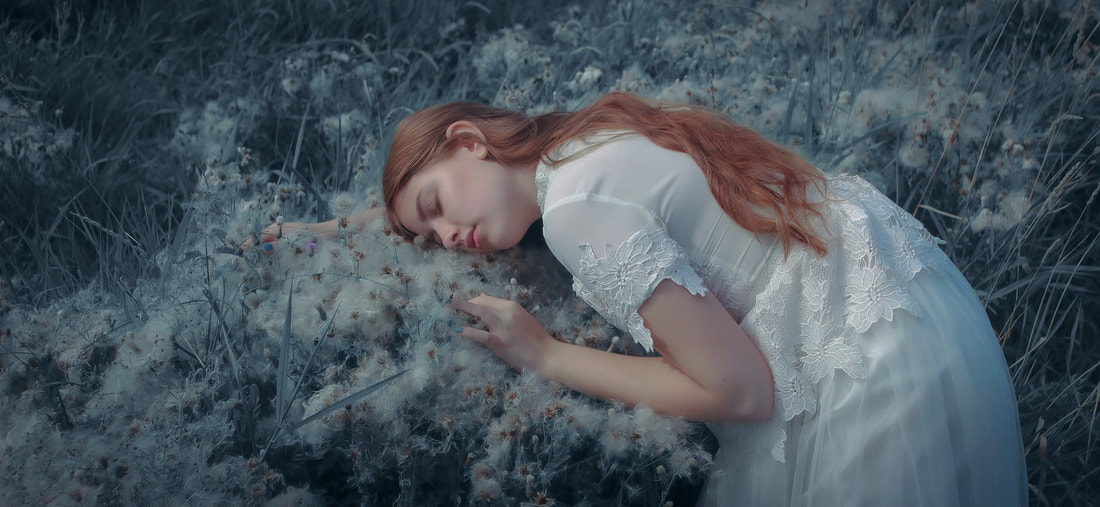Red head girl in white dress laying in grass. 