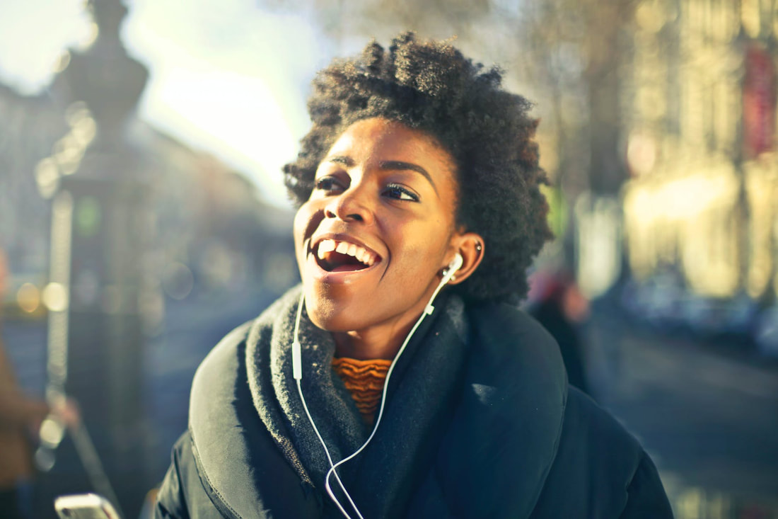 Black woman smiling with earbuds in.