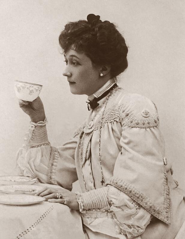 Picture of Victorian woman with dark hair sitting and drinking tea.